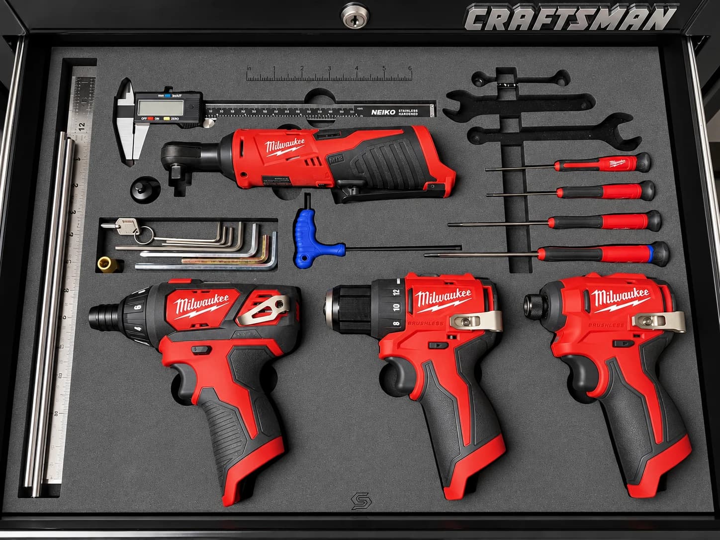 Charcoal foam drawer insert fitted around red power tools, screwdrivers, a caliper, and hex keys.